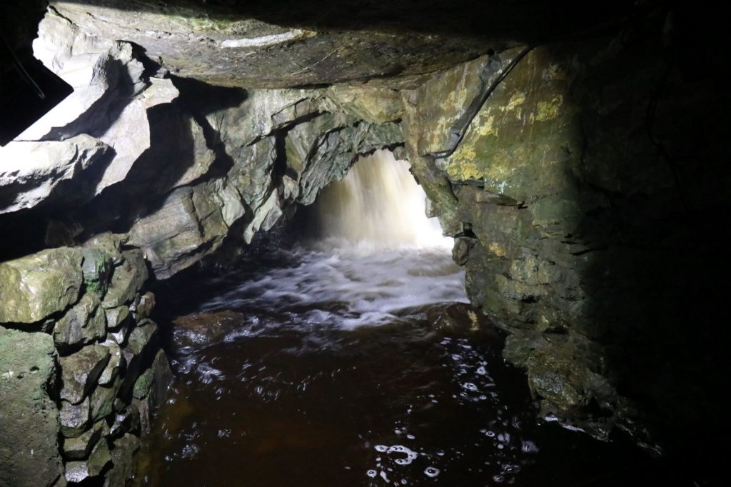 Waterfall behind an underground arch