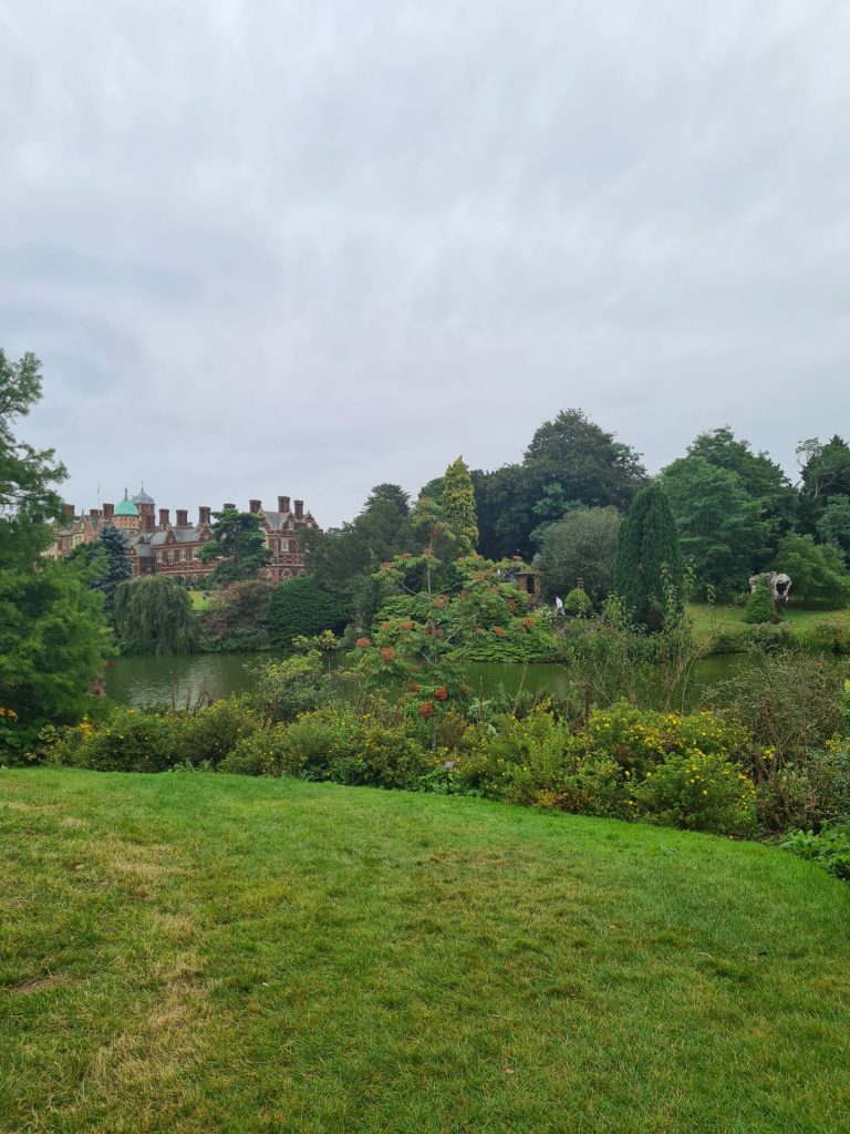 Sandringham House behind plant life and a small lake