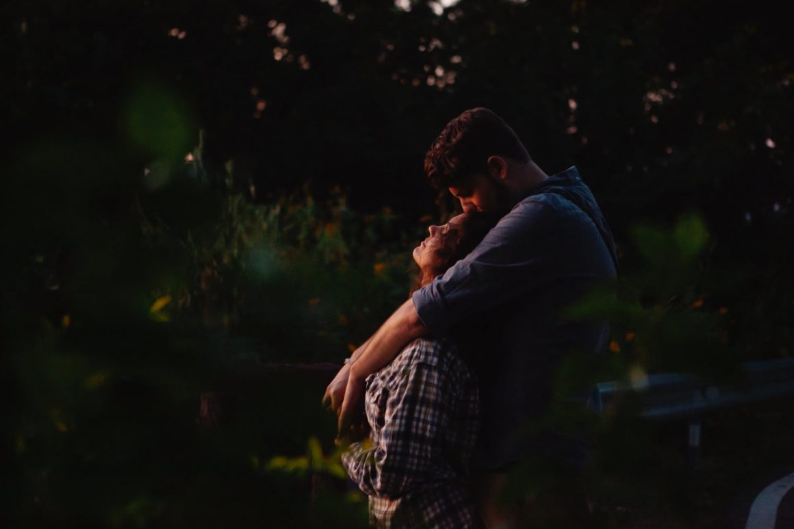loving young couple embracing in forest at sunset