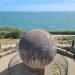 Large stone globe in circular platform in front of sea
