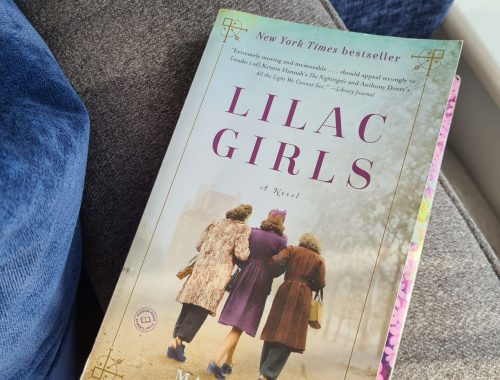 Front cover of Lilac Girls paperback - three women in 1940s clothing shown from behind in centre of book cover, and title printed in purple font