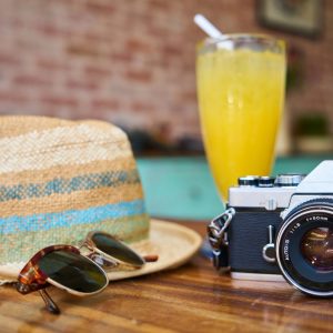 Hat, sunglasses, cocktail and camera on a table