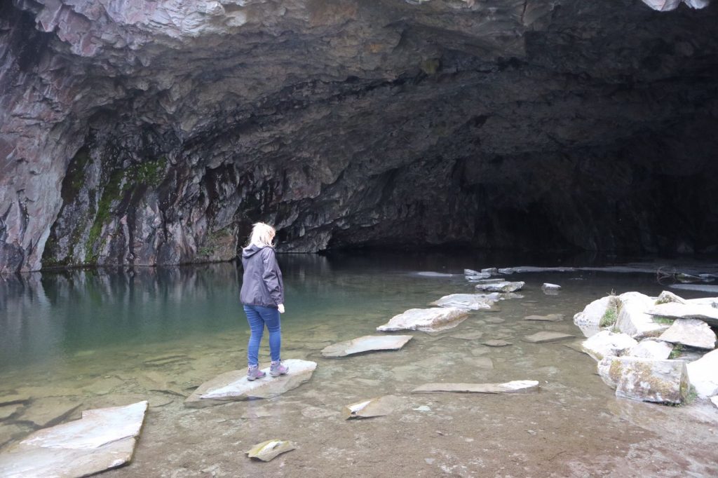 Woman walking on stepping stones on water in a cave on Grasmere to Rydal walk